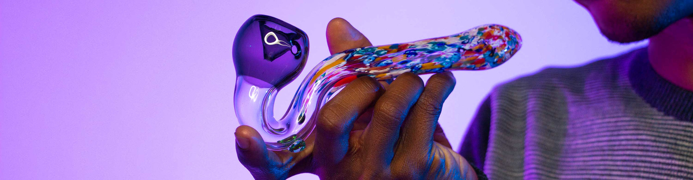 Man holding Sherlock Hand Pipe inside studio with purple lighting